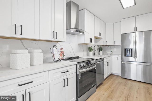 205 Yoakum Pkwy Unit 1712, Alexandria, VA 22304 - kitchen with appliances with stainless steel finishes, wall chimney exhaust hood, white cabinetry, light stone countertops, and light wood-style flooring