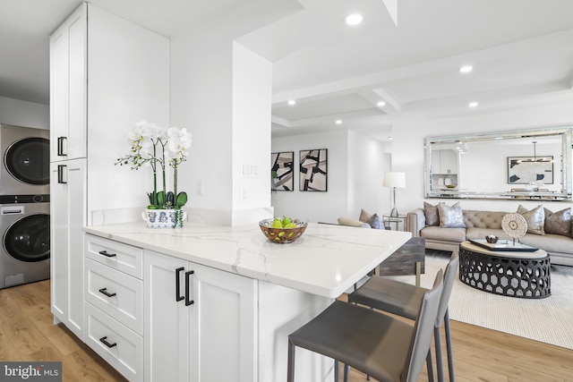 205 Yoakum Pkwy Unit 1712, Alexandria, VA 22304 - kitchen featuring stacked washer / dryer, light stone counters, white cabinets, a kitchen bar, and recessed lighting