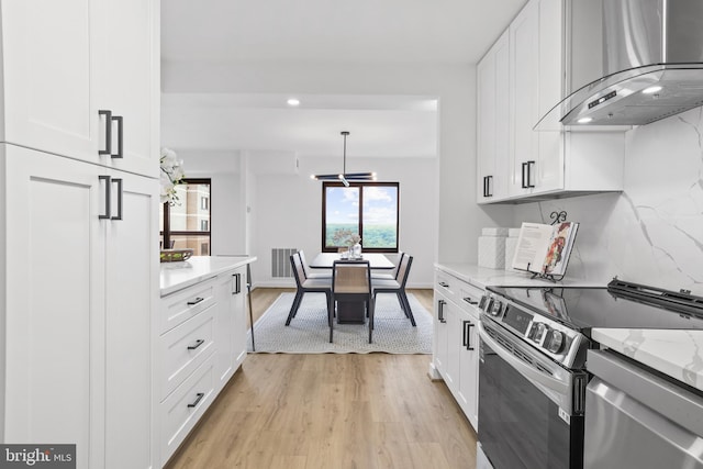 205 Yoakum Pkwy Unit 1712, Alexandria, VA 22304 - kitchen with wall chimney range hood, stainless steel appliances, light wood-style floors, white cabinetry, and recessed lighting
