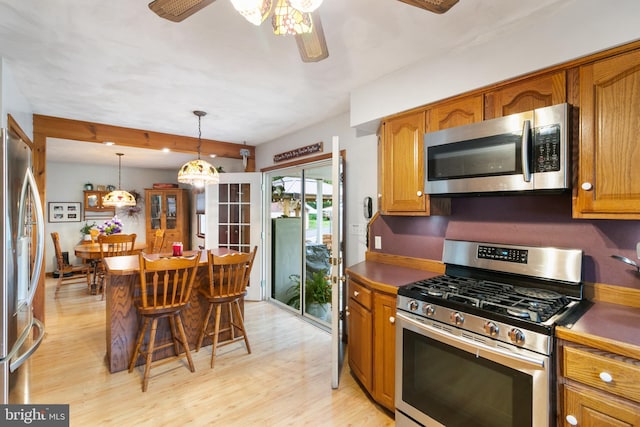 848 Rapp Rd, Howard, PA 16841 - kitchen with stainless steel appliances, light wood-style flooring, brown cabinets, a breakfast bar, and ceiling fan