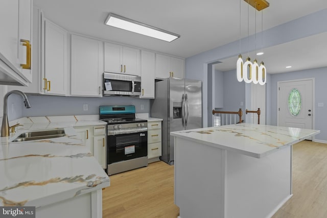 7306 Gavin St, Hyattsville, MD 20784 - kitchen with stainless steel appliances, light wood-style floors, white cabinetry, hanging light fixtures, and a center island