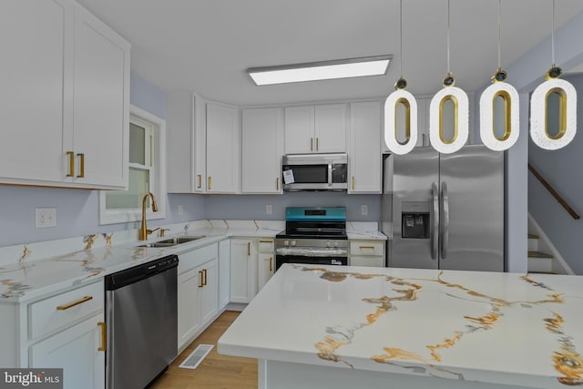 7306 Gavin St, Hyattsville, MD 20784 - kitchen with stainless steel appliances, light wood-style floors, white cabinets, and light stone countertops