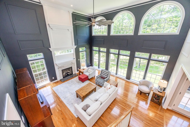 1568 Tattersall, West Chester, PA 19380 - living room featuring a fireplace with raised hearth, ceiling fan, a high ceiling, light wood-style floors, and ornamental molding