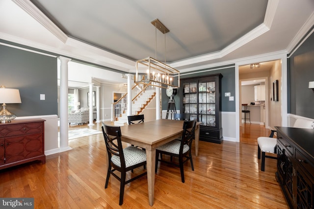 1568 Tattersall, West Chester, PA 19380 - dining space featuring decorative columns, a tray ceiling, stairway, crown molding, and light wood-type flooring