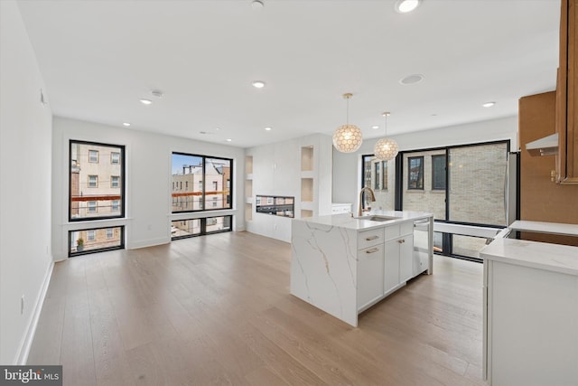 919 S 11th St Unit A, Philadelphia, PA 19147 - kitchen with stainless steel dishwasher, light wood-style floors, under cabinet range hood, an island with sink, and white cabinets
