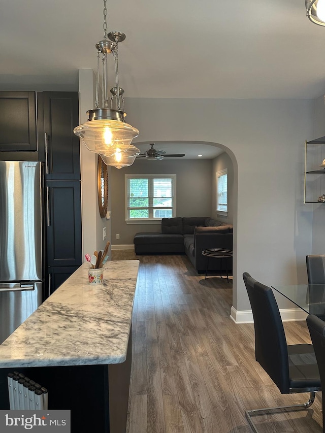 4627 12th St NE, Washington, DC 20017 - kitchen with freestanding refrigerator, arched walkways, dark wood-style flooring, and light stone countertops
