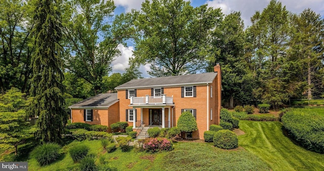 1517 Tuba Ct, Vienna, VA 22182 - colonial home with a balcony, a chimney, a front lawn, and brick siding