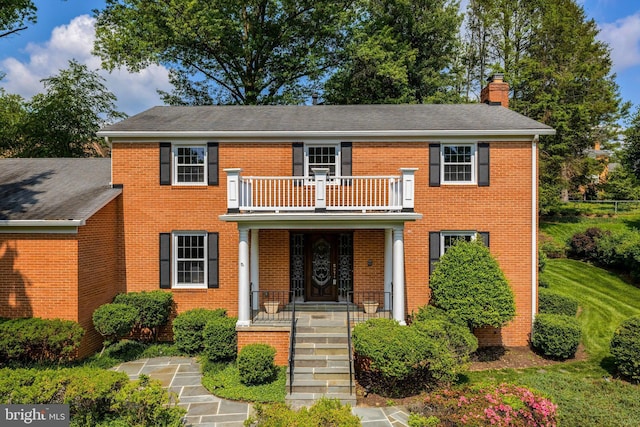 1517 Tuba Ct, Vienna, VA 22182 - colonial-style house featuring a balcony, a chimney, brick siding, and covered porch