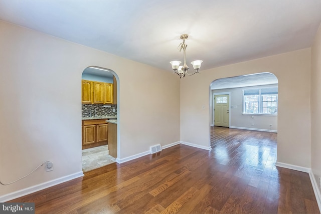 2864 Cushing Rd, Camden, NJ 08104 - spare room with arched walkways, wood finished floors, and a chandelier