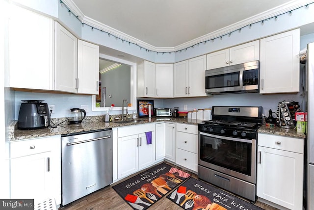 2129 Fort Donelson Ct, Dumfries, VA 22026 - kitchen with appliances with stainless steel finishes, white cabinetry, dark wood-style floors, dark stone counters, and crown molding