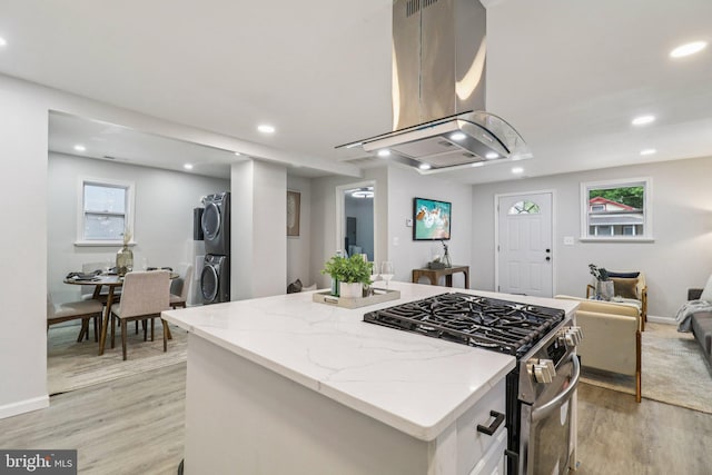 919 Mentor Ave, Capitol Heights, MD 20743 - kitchen with island exhaust hood, stainless steel gas range oven, estacked washer and dryer, light wood finished floors, and open floor plan