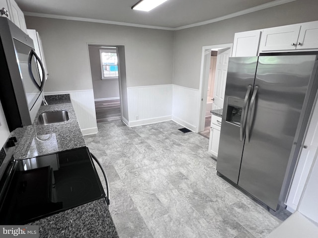 122 W N St, Waynesboro, PA 17268 - kitchen with stainless steel appliances, ornamental molding, a wainscoted wall, white cabinetry, and dark stone counters