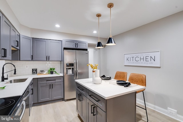 3910 E Pratt St, Baltimore, MD 21224 - kitchen with appliances with stainless steel finishes, light wood finished floors, gray cabinetry, backsplash, and a desk