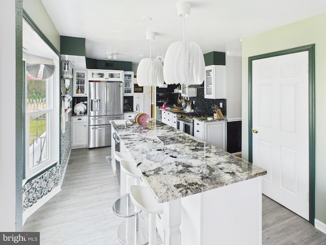2101 Waterleaf Way, Bowie, MD 20721 - kitchen with appliances with stainless steel finishes, white cabinets, a center island, backsplash, and light stone counters