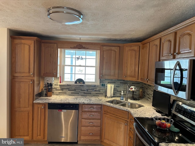 27 Dunlin Way, Sicklerville, NJ 08081 - kitchen with appliances with stainless steel finishes, backsplash, light stone countertops, a textured ceiling, and brown cabinets