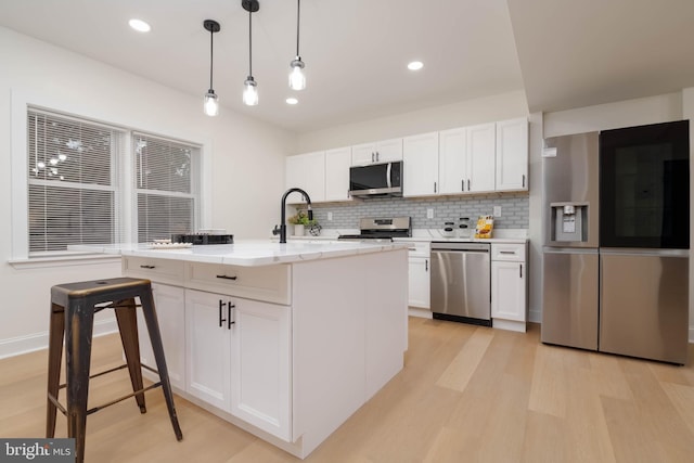 1117 Overbrook Rd, Baltimore, MD 21239 - kitchen featuring stainless steel appliances, light wood finished floors, backsplash, white cabinetry, and decorative light fixtures