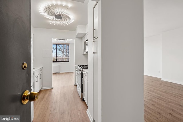 600 Roosevelt Blvd Unit 316, Falls Church, VA 22044 - kitchen with stainless steel range with gas stovetop, white cabinets, light wood-style floors, light countertops, and a chandelier