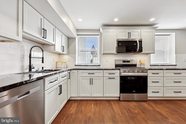 181 Levering St, Philadelphia, PA 19127 - kitchen with stainless steel appliances, backsplash, dark stone counters, dark wood-style flooring, and white cabinetry