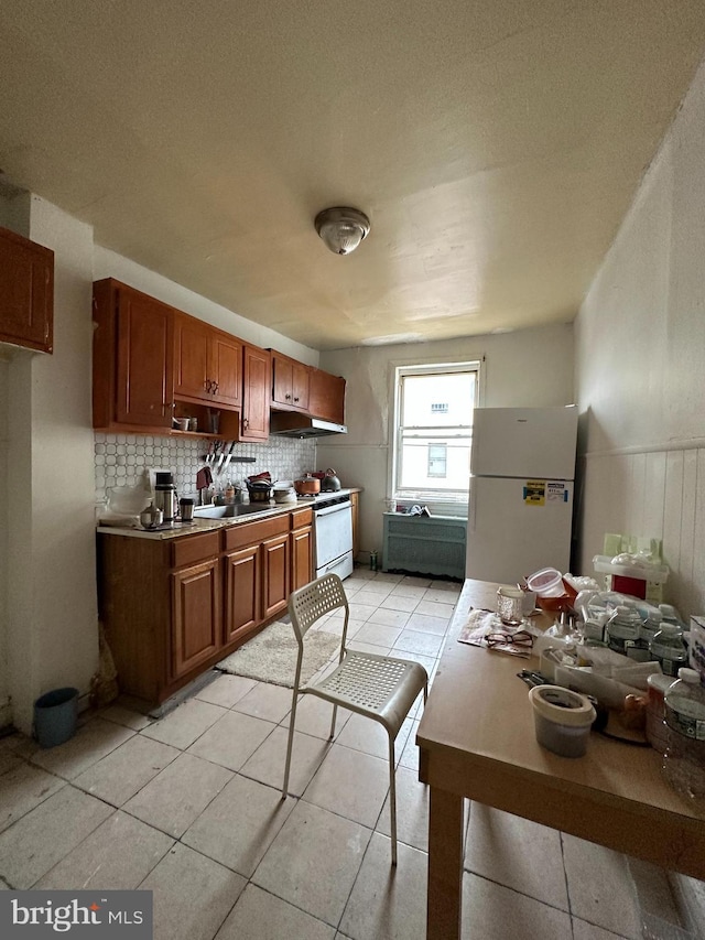 1825 S 8th St, Philadelphia, PA 19148 - kitchen with freestanding refrigerator, light tile patterned flooring, brown cabinetry, decorative backsplash, and under cabinet range hood