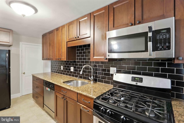 3714 Greenvale Rd, Baltimore, MD 21229 - kitchen with appliances with stainless steel finishes, backsplash, light stone countertops, and brown cabinetry