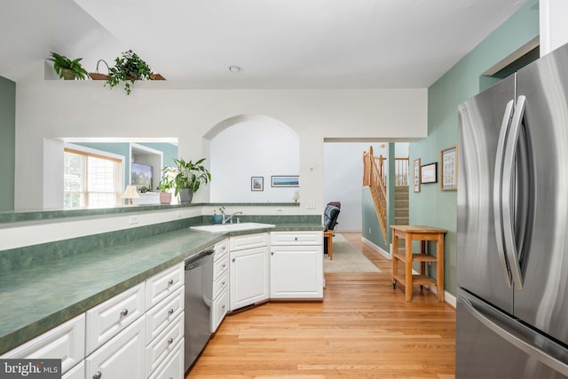 4 Monument Dr, Stafford, VA 22554 - kitchen with stainless steel appliances, light wood-style floors, dark countertops, white cabinetry, and arched walkways