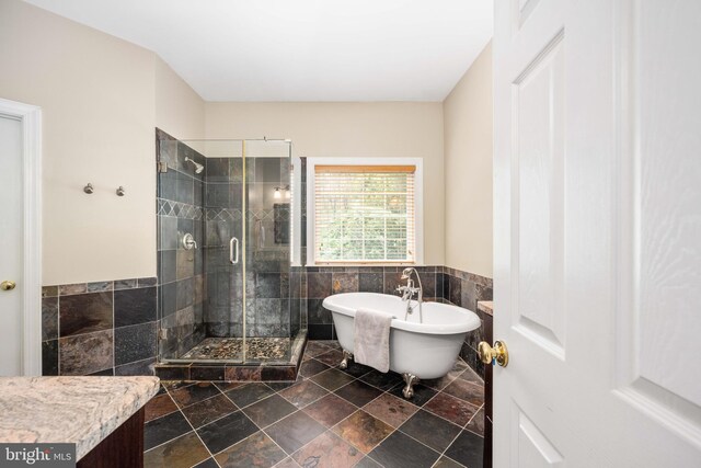 4 Monument Dr, Stafford, VA 22554 - full bathroom featuring a stall shower, a soaking tub, tile walls, a wainscoted wall, and stone finish flooring