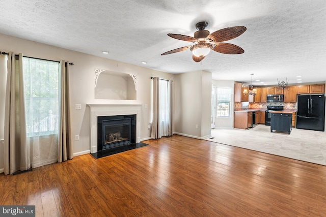 135 Hobbs Hole Ln, Tappahannock, VA 22560 - unfurnished living room with a textured ceiling, a fireplace with flush hearth, light wood-style floors, ceiling fan, and recessed lighting