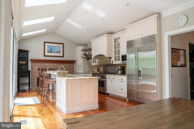 3259 Chrisland Dr, Annapolis, MD 21403 - kitchen with premium appliances, glass insert cabinets, light wood-style flooring, a skylight, and light stone counters