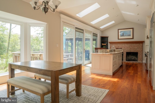 3259 Chrisland Dr, Annapolis, MD 21403 - dining space with lofted ceiling, a chandelier, light wood finished floors, a skylight, and a brick fireplace