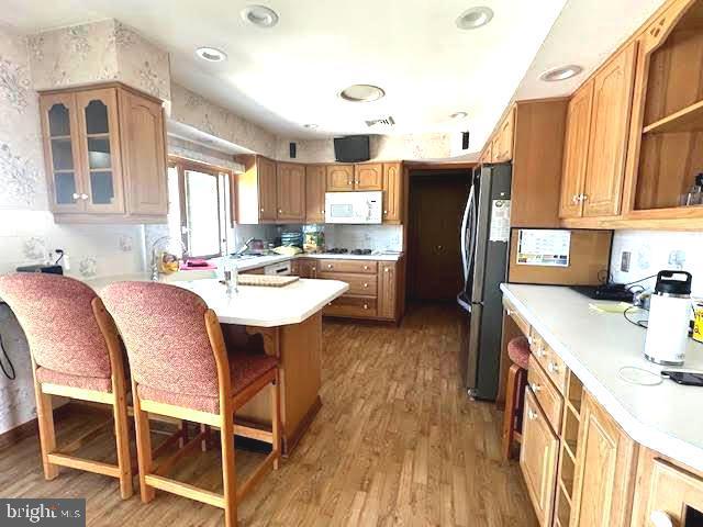32 Saranac Rd, Hamilton, NJ 08619 - kitchen with white microwave, freestanding refrigerator, a peninsula, a kitchen bar, and wood finished floors