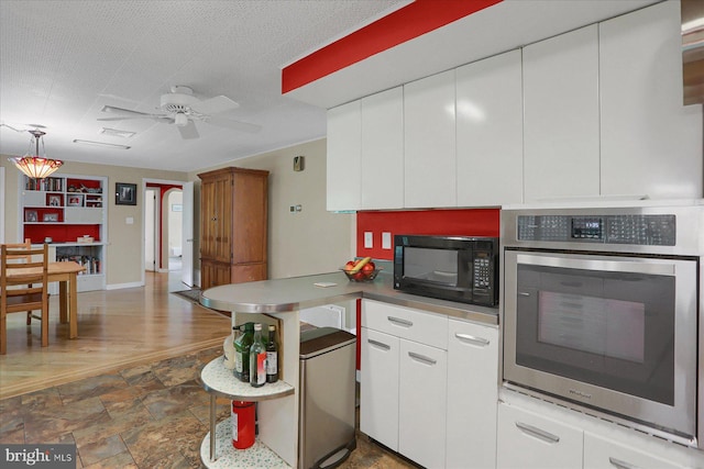 1134 William St, State College, PA 16801 - kitchen with stainless steel oven, black microwave, white cabinets, a ceiling fan, and a peninsula