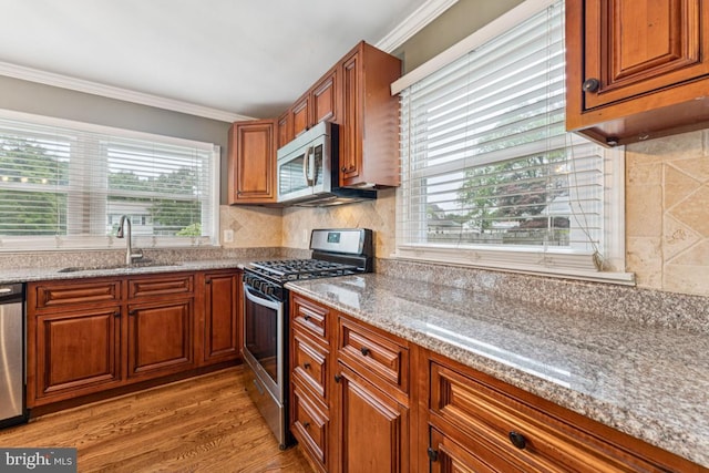 5 Brookfield Rd, Pasadena, MD 21122 - kitchen featuring appliances with stainless steel finishes, brown cabinetry, crown molding, light wood-style floors, and light stone counters