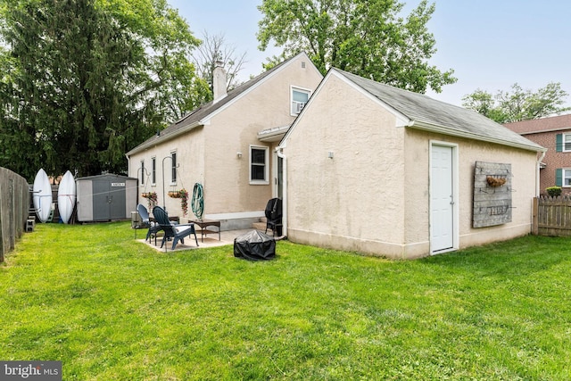 101 Ash Rd, Wallingford, PA 19086 - back of property with a fenced backyard, stucco siding, an outdoor fire pit, and a storage unit