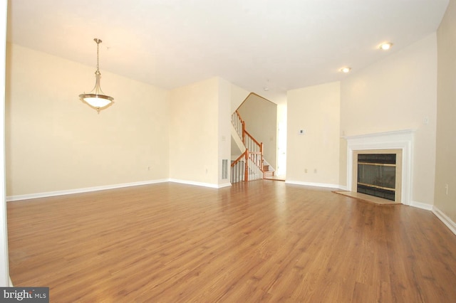 12013 Panthers Ridge Dr, Germantown, MD 20876 - unfurnished living room featuring light wood-style flooring, stairs, and a glass covered fireplace