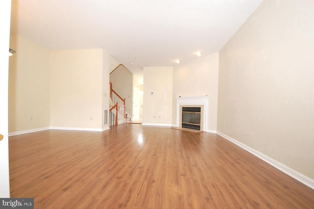 12013 Panthers Ridge Dr, Germantown, MD 20876 - unfurnished living room with light wood finished floors, stairs, and a fireplace with flush hearth