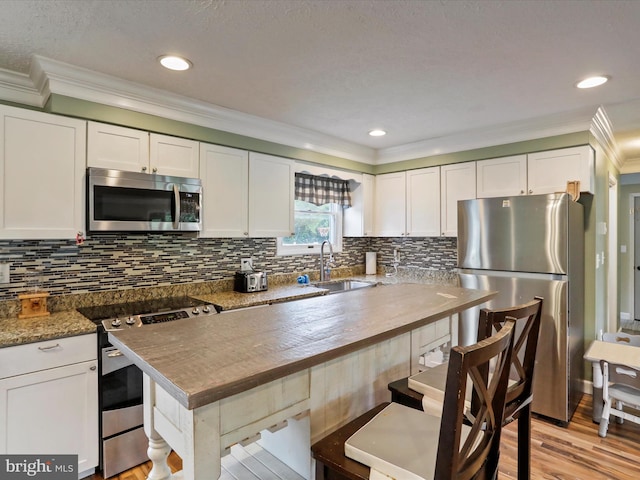 15 Nightingale St, Keyser, WV 26726 - kitchen featuring appliances with stainless steel finishes, ornamental molding, a kitchen breakfast bar, white cabinetry, and backsplash