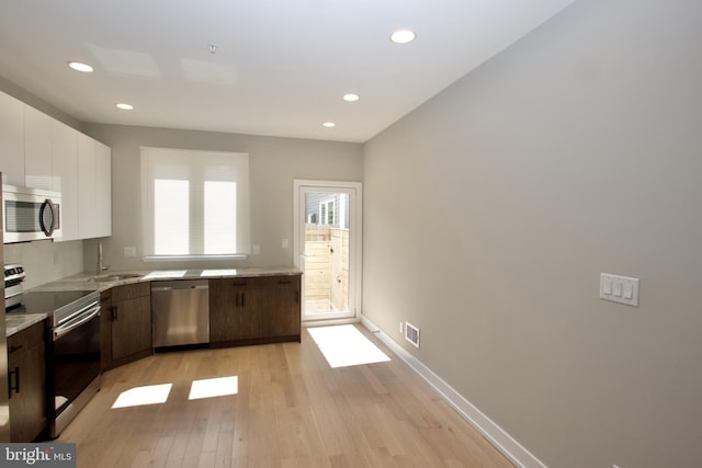 2417 N Hancock St, Philadelphia, PA 19133 - kitchen with appliances with stainless steel finishes, light wood-style floors, recessed lighting, white cabinetry, and light stone counters