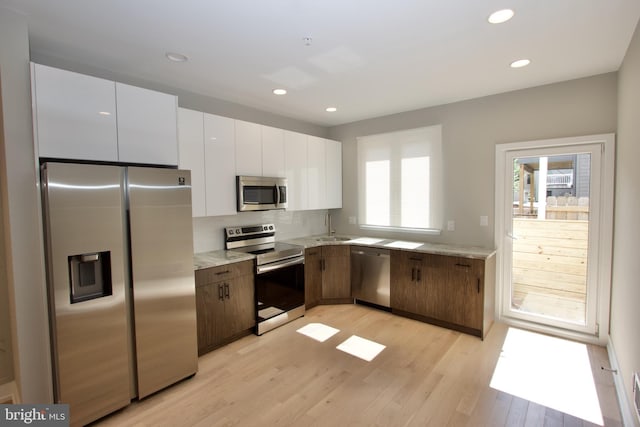 2417 N Hancock St, Philadelphia, PA 19133 - kitchen featuring appliances with stainless steel finishes, white cabinets, light wood-type flooring, tasteful backsplash, and recessed lighting
