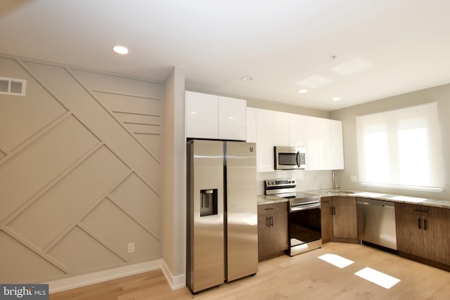 2417 N Hancock St, Philadelphia, PA 19133 - kitchen with stainless steel appliances, light wood finished floors, white cabinetry, backsplash, and recessed lighting