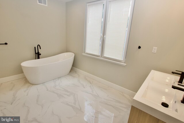2417 N Hancock St, Philadelphia, PA 19133 - full bathroom featuring marble look tiles, a soaking tub, and double vanity