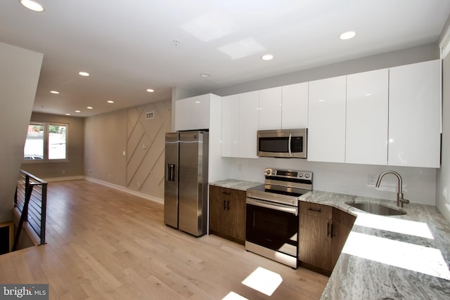 2417 N Hancock St, Philadelphia, PA 19133 - kitchen with stainless steel appliances, light wood-style floors, white cabinets, modern cabinets, and light stone countertops