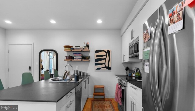 1800 S 16th St Unit B, Philadelphia, PA 19145 - kitchen featuring appliances with stainless steel finishes, dark countertops, a peninsula, wood finished floors, and recessed lighting