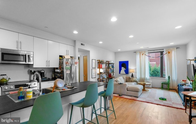 1800 S 16th St Unit B, Philadelphia, PA 19145 - kitchen with stainless steel appliances, dark countertops, a breakfast bar, white cabinetry, and light wood-type flooring