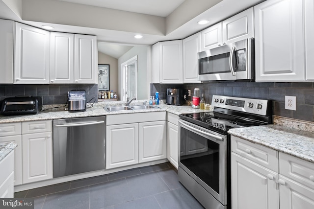 94 E Oak Ave, Lawnside, NJ 08045 - kitchen with appliances with stainless steel finishes, dark tile patterned floors, white cabinets, recessed lighting, and lofted ceiling