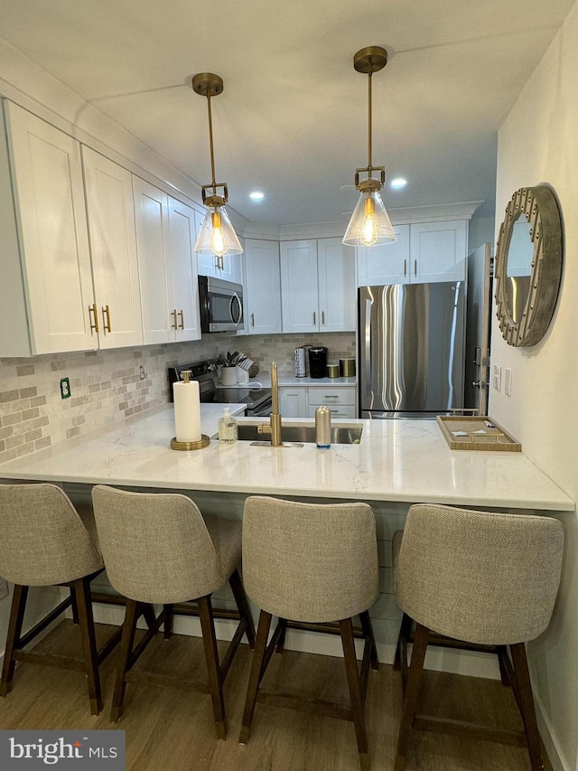 35979 Condo Dr Unit 203B, Rehoboth Beach, DE 19971 - kitchen featuring appliances with stainless steel finishes, a peninsula, white cabinets, wood finished floors, and recessed lighting