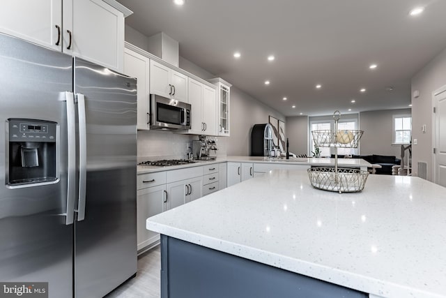 7282 Nittany Ln, Alexandria, VA 22306 - kitchen featuring appliances with stainless steel finishes, recessed lighting, a peninsula, backsplash, and light stone counters