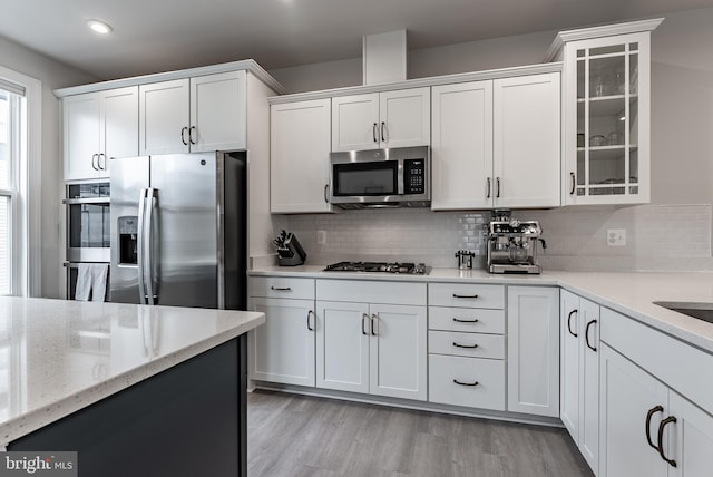 7282 Nittany Ln, Alexandria, VA 22306 - kitchen featuring stainless steel appliances, white cabinets, glass insert cabinets, decorative backsplash, and light stone counters