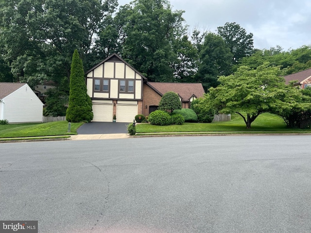 6012 Burnside Landing Dr, Burke, VA 22015 - english style home featuring an attached garage, driveway, a front yard, stucco siding, and view of wooded area
