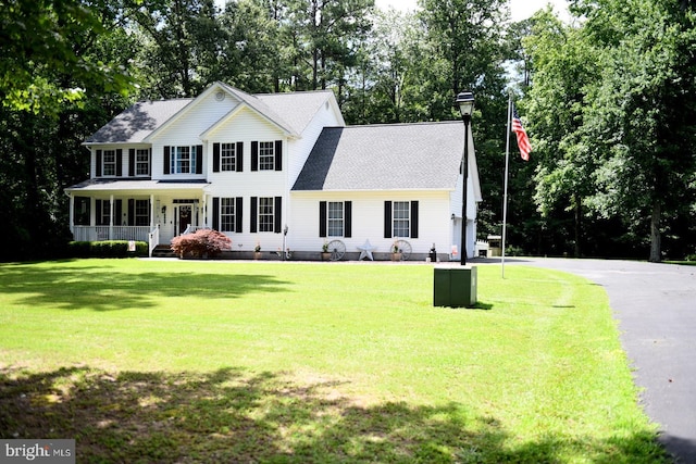 21481 Indian Bridge Rd, California, MD 20619 - colonial home with a front yard, view of wooded area, a porch, and a shingled roof