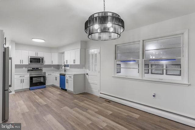 708 S Broad St, Mechanicsburg, PA 17055 - kitchen with appliances with stainless steel finishes, baseboard heating, light countertops, white cabinets, and light wood finished floors